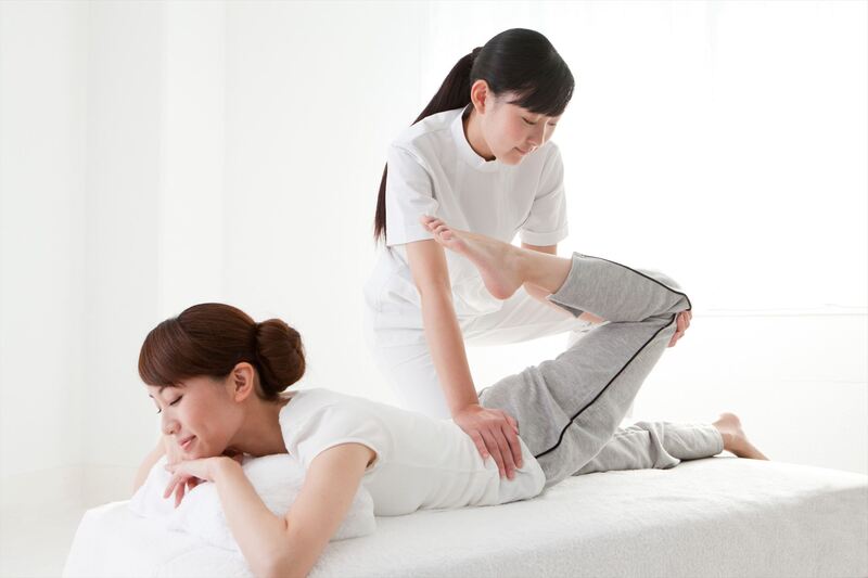 女性の左足を施術するスタッフ